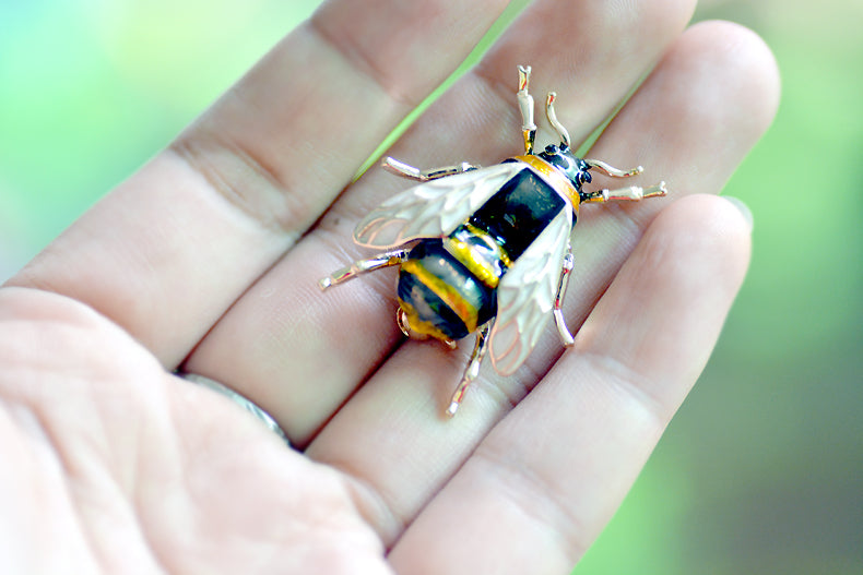 shiny enamel bee pin in hand