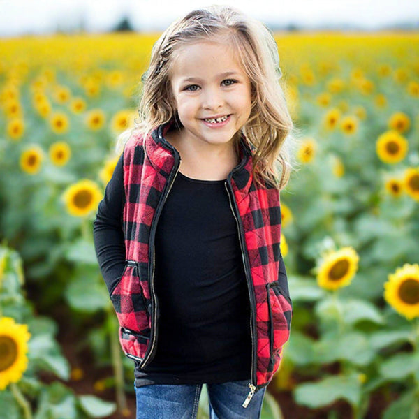Child wearing plaid vest among sunflowers